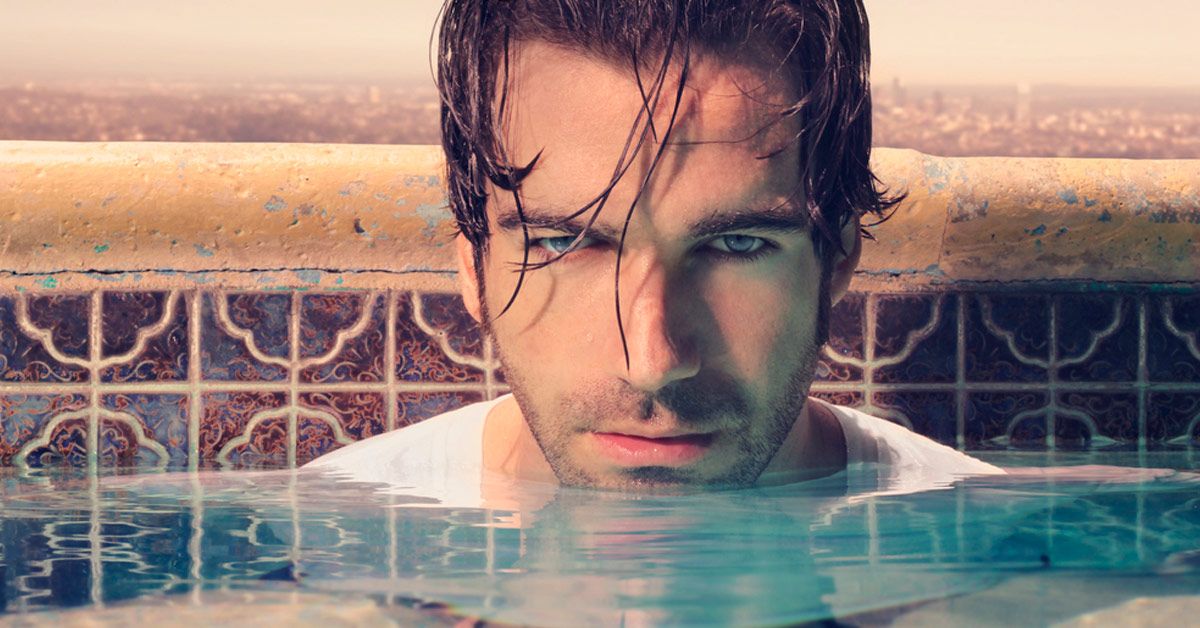 Man with wet hair in pool water.